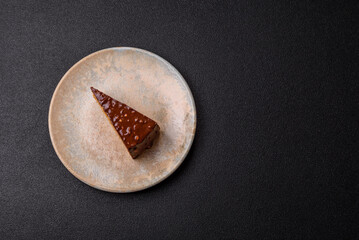 A slice of sweet layered cake covered in chocolate with nuts and caramel. A slice of chocolate cake