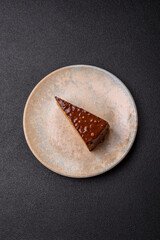 A slice of sweet layered cake covered in chocolate with nuts and caramel. A slice of chocolate cake