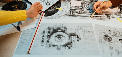 This image captures a collaborative engineering session where hands engage with technical drawings...