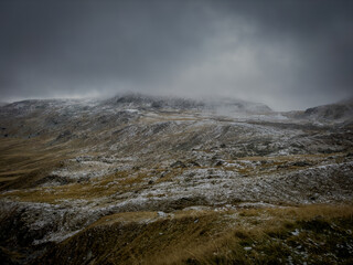 Windblown snowy mountain plateau, heavy clouds