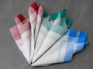Unfolded three folded handkerchiefs in colors of red, green, and blue, each with a grey center and a plaid pattern, displayed against a solid gray background.