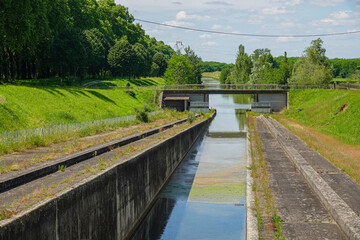 Fototapeta premium Canal de Montech in France with concrete banks, grassy edge, and bridge