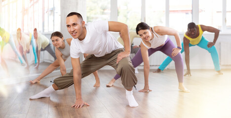 Obraz premium Group of multicultural men and women doing warm-ups before dance class in studio