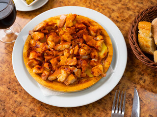 Cooked octopus with potatoes in close-up. Traditional Galician dish Pulpo a la gallega on white plate. Spanish seafood dish