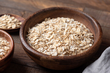 Dry Rolled oats in wooden bowl, healthy dietary fiber