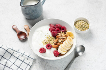 Healthy diet meal, bowl of greek yogurt with raspberries, banana slices, almond nuts and granola