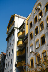Residential building with yellow balconies and windows under blue sky in Novi Sad, Serbia.