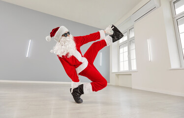Santa Claus man breakdancing wearing red suit and cute funny sunglasses, humorous and energetic dancer, playful holiday spirit party, joyful performing in athletic move alone, white studio gym