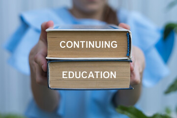 Young girl holding two books with inscription on side: CONTINUING EDUCATION. Continuing Education Business School concept.