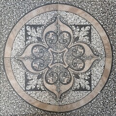 High-resolution photo of ornamental stone floor tile with a circular decorative pattern and pebble texture. Suitable for backgrounds, architecture design references, surface details, and decorative.