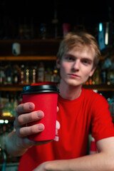 Barista or bartender serving red paper to go coffee cup at coffee shop. Selecive focus on hand. 