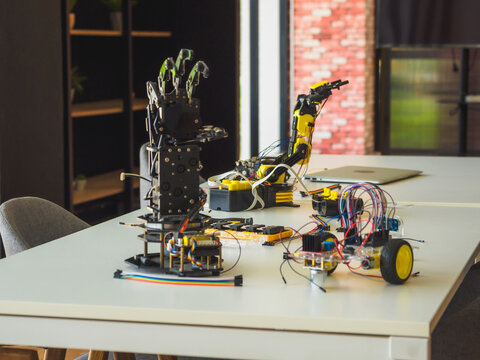 Modern education on classroom for student, interested people robotics workspace with various components and tools on white table, showcasing innovation and technology in a well-lit environment.