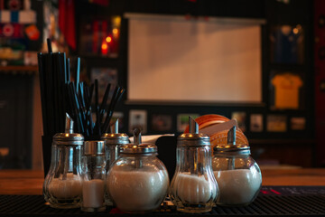 Bar counter with coffee straws and glass jars with sugar in selective focus. Authentic cafe bar in blur. Eco-friendly packaging from recycled and reused materials