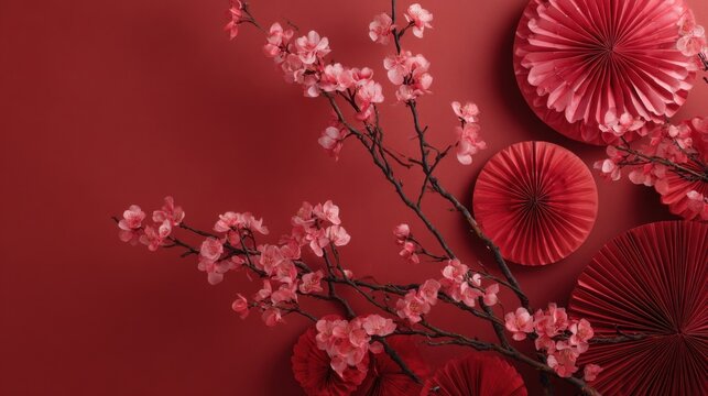 Red cherry blossom branch with pink flowers and decorative paper fans on a bold red background