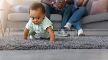 Portrait of adorable cute baby boy learning how to walk at home, crawling on rug floor carpet,...
