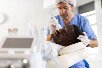 African-American man during facial skin care procedure. Stage of skin rejuvenation is to reduce...