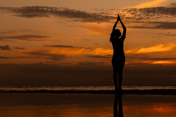 yoga and meditation. woman plays sports at sunset on the ocean. women's does stretching of the lateral muscles, preparing for a marathon. fitness and yoga in the park, silhouette.