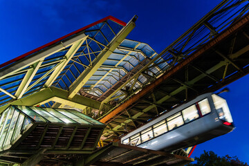 Fototapeta premium Nachtaufnahme der Wuppertaler Schwebebahn an der Haltestelle Kluse, Wuppertal, Deutschland