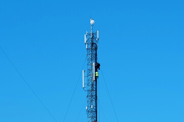 Obraz premium Three workers repair a cell tower. Laying new cables. High-altitude work