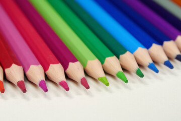 New wooden colored pencils of rainbow colors, perfectly sharpened, lie on table