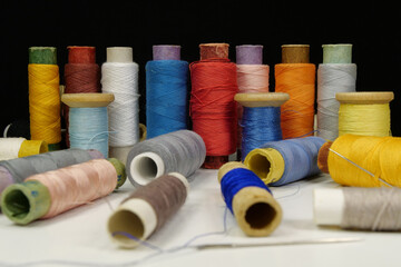 Spools with multi-colored threads on black background, close-up shot
