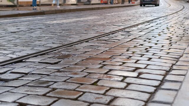 Red tram passing on cobblestone street. Vintage red tram gliding along wet cobblestone street, rails stretching into perspective, capturing urban transportation atmosphere