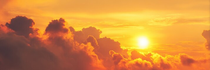 Fototapeta premium Colorful clouds filled with golden and orange hues are illuminated by the sun as it sets on the horizon, creating a tranquil evening atmosphere.