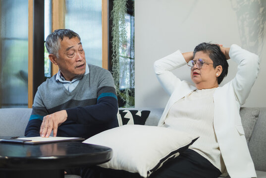 Elderly couple man and woman sit on sofa in cozy living room, use tablet together. appear be engaged in activity on tablet, possibly read browse internet plan your life, business or health insurance.