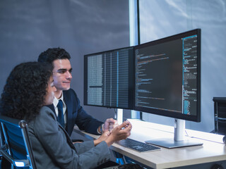 Man and woman team business professional formal attire collaborate desk with dual monitor computer talk about financial stock market in modern office highlight teamwork technology, professional work