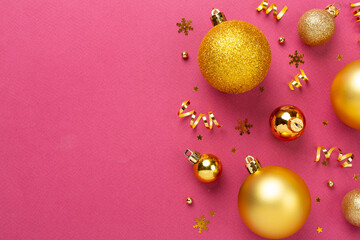 Golden Christmas balls with decor on color background, top view