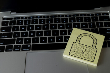 A lock icon on a sticky note over a laptop keyboard. A concept for cybersecurity, internet safety, and protecting personal or corporate data from hackers and cyber attacks.