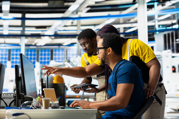 Group of black employees finetuning the manufacturing process of solar cells at the facility, doing...