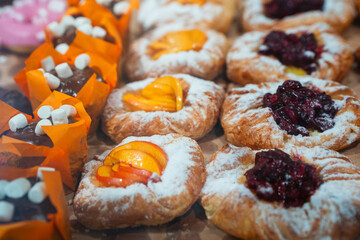A selection of pastries topped with fruit slices, berry compote, and chocolate with marshmallows, arranged on a tray. Suitable for bakery promotion, food blogs, or menu design.