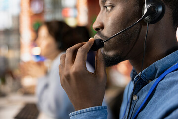 Call center operator talking in audio headset mic, providing step by step guide to customer. African american customer center employee speaking in headphones microphone, providing solutions, closeup