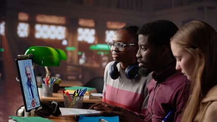 Diverse students group engaging in a video call with physician, learning about medical topics and methods. Medicine pupils utilizing telemedicine tools for remote learning in a library. Camera A.