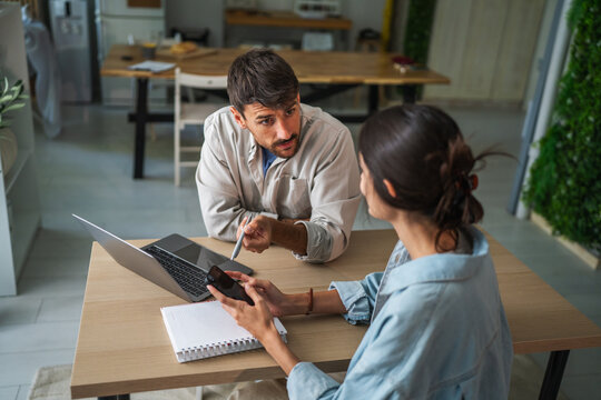 Couple working from home using laptop and smart phone