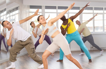 Naklejka premium Active sporty multinational men and women of different ages practicing Hip-hop dance in training hall during dancing classes