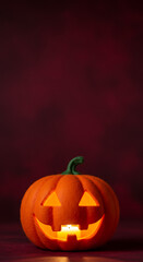 Fototapeta premium Halloween pumpkin lantern with carved face glowing on dark background - Cute felt pumpkins and other Halloween toys.