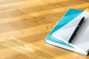 木製デスクに置かれたノートとペンとメモ用紙