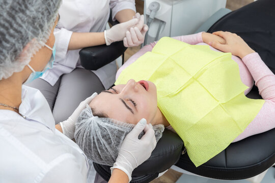 Dentist and assistant performing dental treatment inmodern dental clinic, patient laying in a chair