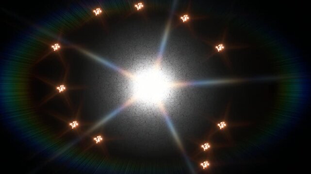 Bright central starburst with a circular ring of glowing points against a dark rainbow halo. In view