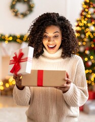 A person joyfully opening a gift box. The person displays a surprised and delighted expression while looking inside the box. Room is softly lit with blurred Christmas lights and holiday decorations.