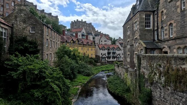 footage video of Dean Village in Edinburgh, Scotland, a picturesque historic riverside settlement along the Water of Leith with stone bridges, medieval buildings, and lush green valley views.