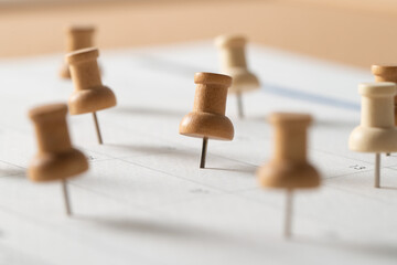 Wooden push pins marking important dates on a calendar, symbolizing planning, scheduling, reminders, and organization.