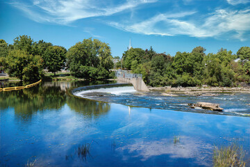 Waterfall with small hydro electric generation, daytime, blue skies and clouds, church in distance, nobody
