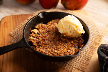 Apple oat crumble, walnuts, butter and brown sugar with vanilla ice cream topping, homemade recipe, traditional dessert perfect for the winter season made in a cast iron skillet.
