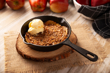 Apple oat crumble, walnuts, butter and brown sugar with vanilla ice cream topping, homemade recipe, traditional dessert perfect for the winter season made in a cast iron skillet.