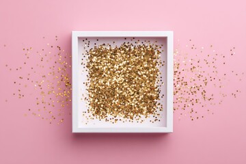 A square white frame filled with gold glitter sits on a pink background, with scattered glitter