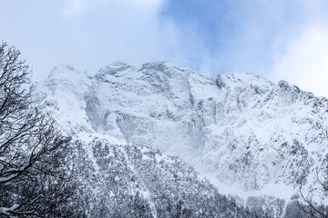 Obraz premium Snow-covered mountain peaks against a blue winter sky
