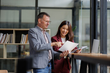 Two business working together using digital tablet pc and talking about a business project. Small creative diversity team of females executives meeting work in office.
